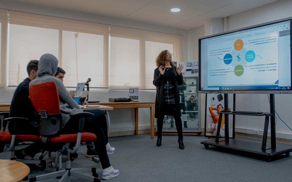 Session de formation d’adultes devant un écran interactif sur pied mobile.